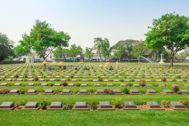 KANCHANABURI THAILAND - 21 Şubat: Kimliği belirsiz işçiler, 21 Şubat 2020 'de Kanchanaburi, Tayland' daki Kanchanaburi Müttefik Savaş Mezarlığı 'nda çiçek yenileyip dekore ediyorlar