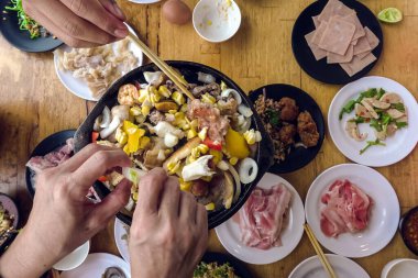 Barbekü Barbeküsü yemek. İnsanlar domuz eti, yemek, kabuklu deniz ürünleri ve karidesleri kızgın siyah tavada pişirecek yağ ve tereyağı ile kızgın fırında kızartıyorlar. Bir restoranda tatil yemeği..