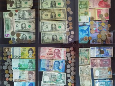 Cam masadaki çeşitli ülkelerden toplanan ve sergilenen para ve banknotların üst görünümü. Dünyanın çeşitli ülkelerinden gelen banknotların koleksiyonu. Farklı devlet parası..