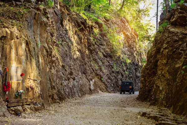 Tourist SUV car cruising along a rugged route through the gorge that was once a former railway line built by prisoners of war during the World War 2 at Hellfire Pass in Kanchanaburi Province,Thailand.
