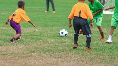 Futbolcu çocuklar antrenman kursu. Bir tarlada futbol oynayan anaokulu öğrencileri. Spor sahasında koşan ve futbol oynayan bir grup çocuk. Futbol maçında çocuklar spor giyer..