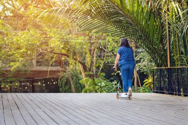 Asyalı kadın evde güvenlik donanımı kullanmadan modern ekstrem dublör scooter sürmeyi ve oynamayı seviyor. Genç bir kadının aktif spor yaşam tarzı. Mutlu kadın kasksız scooter kullanıyor..