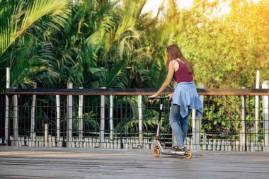 Asyalı kadın evde güvenlik donanımı kullanmadan modern ekstrem dublör scooter sürmeyi ve oynamayı seviyor. Genç bir kadının aktif spor yaşam tarzı. Mutlu kadın kasksız scooter kullanıyor..
