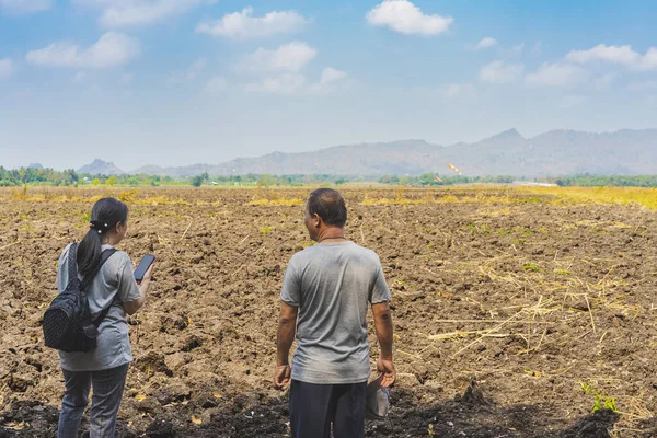 Back view of Asian couple farmers discuss soil quality for farming in soil field. Lovers agriculturist consult each other about cultivation in meadow. Farm and agricultural business after retirement.