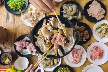 Barbekü Barbeküsü yemek. İnsanlar domuz eti, yemek, kabuklu deniz ürünleri ve karidesleri kızgın siyah tavada pişirecek yağ ve tereyağı ile kızgın fırında kızartıyorlar. Bir restoranda tatil yemeği..