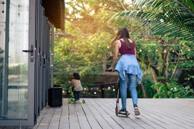 Asyalı kadın evde güvenlik donanımı kullanmadan modern ekstrem dublör scooter sürmeyi ve oynamayı seviyor. Genç bir kadının aktif spor yaşam tarzı. Mutlu kadın kasksız scooter kullanıyor..