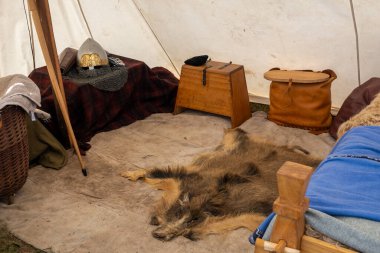 Zeminde hayvan kürkü ve yaşam tarzı objeleri olan bir Viking çadırının kopyası. Yeniden canlandırma topluluğu panayırındaki ağ başlıklı objeler de buna dahil.
