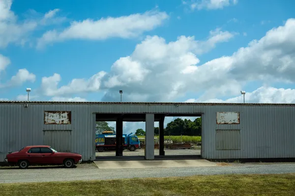 2021年10月 澳大利亚昆士兰州麦凯 以红色轿车和工业车辆为背景的糖厂维修棚 — 图库照片
