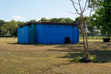 Kırsal bir çayırda parlak mavi boyanmış bir tuvalet bloğu