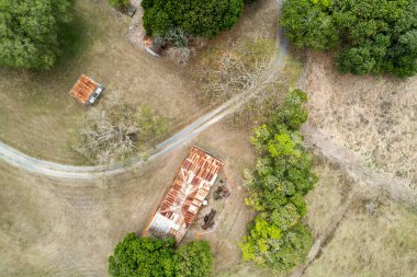 İki barakaya bakıyor ve ağaçların arasında bir patika var.