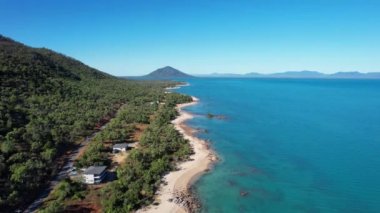 Cape Gloucester Queensland Avustralya 'daki uzun kumlu sahil ve turkuaz mavisi suların yakınındaki evlerin üzerindeki hava manzarası.