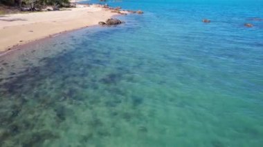Kumlu sahil boyunca alçak hava manzarası ve açık mavi okyanus Cape Gloucester Queensland Avustralya 'da kayalık deniz yatağı.