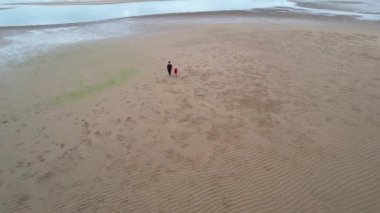 Bucasia Beach, Mackay, Queensland, Avustralya - Haziran 2021: Küçük torunuyla sahilde yürüyen bir büyükanne gelgitte suya doğru el ele tutuşuyor