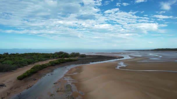 曇り空の下で泥や砂州と干潮時に海に向かって流れる小川を空中から眺めるケープ パーマストン オーストラリア — ストック動画
