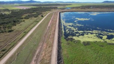 Su yeşili bitki örtüsüyle baraj duvarı boyunca insansız hava uçuşu. Kinchant Barajı, Mackay, Queensland, Avustralya