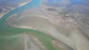 Okyanusun alçak gelgitteki hava görüntüleri, kumsalları ve deniz suyunu soyut şekillerde gösteriyor. Cape Hillsborough, Queensland, Avustralya