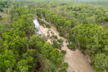 Kuru bir dere yatağının insansız hava aracı görüntüsü ve ormanlık bir derede sadece sığ bir su havuzu var.