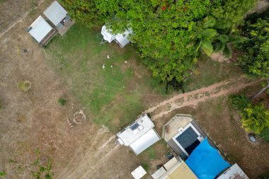 Townsville, Queensland, Avustralya - Kasım 2021: İnsansız hava aracı karavanları, barakaları ve yüzme havuzu olan bir arka bahçeyi tepeden görüyor. Üç çocuk İHA 'nın inmesini bekliyor..