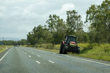 Bruce Highway Mackay Townsville, Queensland, Avustralya 'ya - Kasım 2021: Yol kenarlarındaki çimleri biçmek için traktör kullanan bakım işçisi