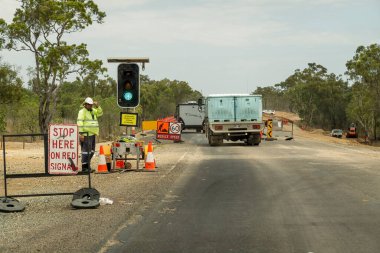 Bruce Highway Mackay 'in Townsville, Queensland, Avustralya' ya gidişi - Kasım 2021: Tabelaların arasında bekleyen bir inşaat işçisiyle yol çalışması için yeşil ışık yakılan araçlar