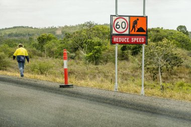 Bruce Highway Mackay Townsville, Queensland, Avustralya 'ya - Kasım 2021: Diğer yönde yürüyen yol çalışması ve inşaat işçisi nedeniyle hız levhasını düşürme