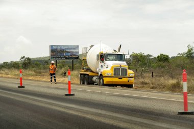 Bruce Highway Mackay 'den Townsville, Queensland, Avustralya' ya - Kasım 2021: İnşaat işçisi yol çalışması ve bir reklam panosunun önüne park etmiş bir kamyonun önünde taksi şoförü ile birlikte yürüyor