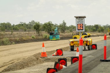Mackay 'dan Townsville Bruce Highway' e, Queensland, Avustralya - Kasım 2021: Yol çalışması konileri, direkler ve makineler arasındaki hızınızı gösteren işaret