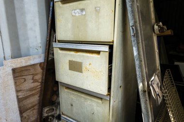 Bir konteynırda depolanmış ıvır zıvırla çevrili eski bir dosya dolabı.