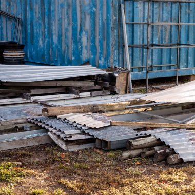 Kenar mahallelerin arka bahçesinde dağınık bir yığın halinde duran kıvrık demir çarşaflar.