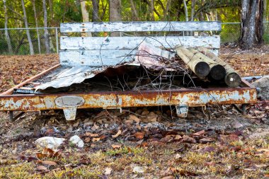 Yaprakların arasında paslanırken çöp dolu eski bir kamyon tepsisi.