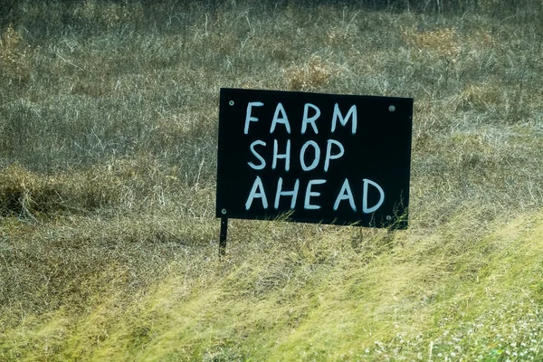 道路脇の草の上に黒い台に白で描かれた先の農家の店の看板の手 — ストック写真