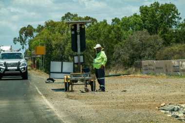 Bruce Highway Townsville 'den Mackay' e, Queensland, Avustralya - Kasım 2021: Otoyol inşaatında trafik ışıklarını denetleyen şişman yol işçisi