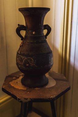 Tarihi bir çiftliğin köşesine yerleştirilmiş eski bir masa üzerindeki eski bir vazo. Fotoğrafçılık çağını kopyalamak için tahıl geliştirme.
