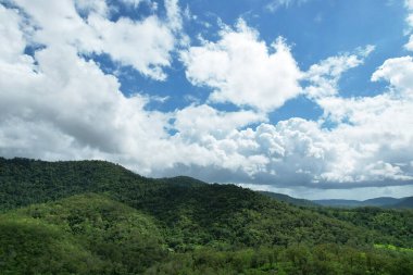 Dağlar yeşil bitki örtüsüyle kaplı bulutlu mavi gökyüzünün altında