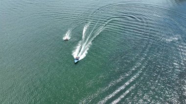 Bir sürat teknesi insanları şişirilebilir borularla barajın sularından geçiriyor.