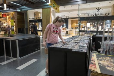 Mackay, Queensland, Avustralya - Aralık 2021: Genç kız alışveriş merkezi koridorundaki bir mağazada mücevher arıyor