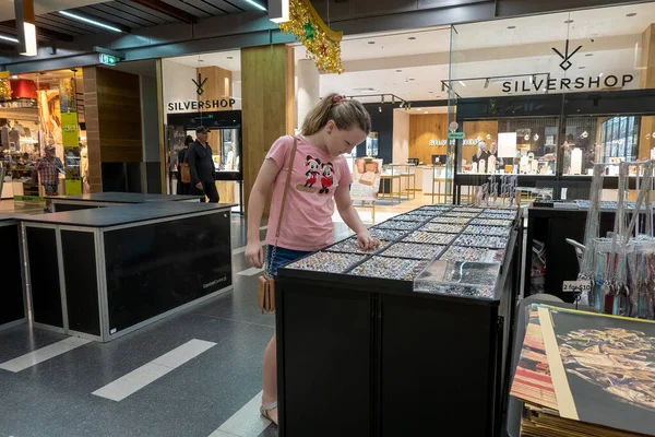 Mackay, Queensland, Avustralya - Aralık 2021: Genç kız alışveriş merkezi koridorundaki bir mağazada mücevher arıyor