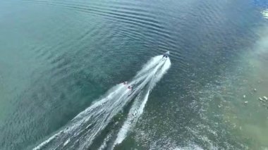 Şişme borularda, motorlu tekne tarafından çekilen iki kişinin insansız hava görüntüsü. Heyecan verici su sporları.