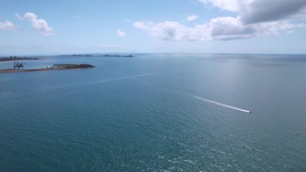 穏やかな青い海の上の石炭輸出ターミナルから曇った空の下で海を渡る小さなパワーボート — ストック動画