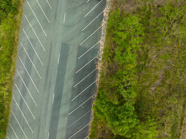 Looking down drone aerial of a vacant car park bordered with bushland