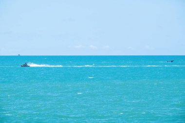 Güneşli bir günde mavi okyanusta kayak yapan bir jet ski.