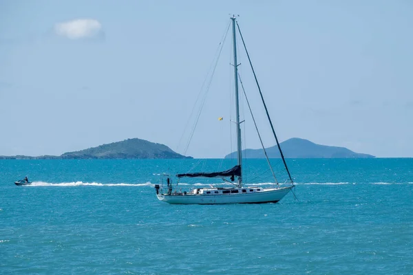 澳大利亚昆士兰州海莉海滩 2021年12月 一架喷气式滑翔机在蓝天的映衬下 将一艘豪华游艇的帆抛锚在海岸外 并以岛屿和山地为背景 为其提供动力 — 图库照片