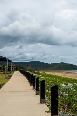 A walking track through a playground beside the ocean under a stormy sky
