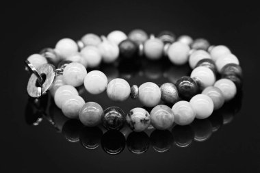 Çok desenli, yeşim taşından bir kolye. Siyah arka planda yuvarlak tokalı, yansımalı. Monoton resim.