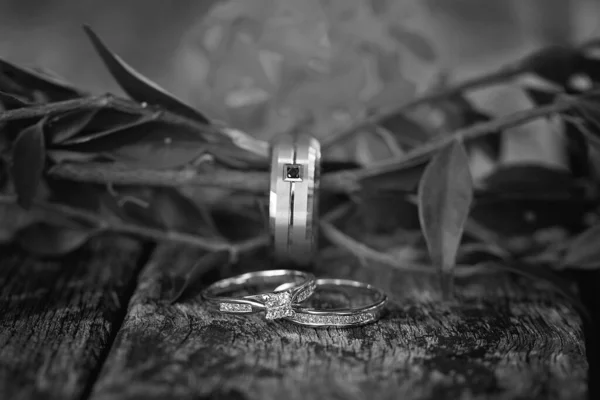 Pierścienie Ślubne Splecione Liśćmi Drewnianej Powierzchni Kwiatowym Tłem — Zdjęcie stockowe