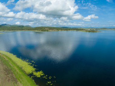 Bulutlar, bir yaz günü, sakin, durgun bir barajın sularına yansıyor..