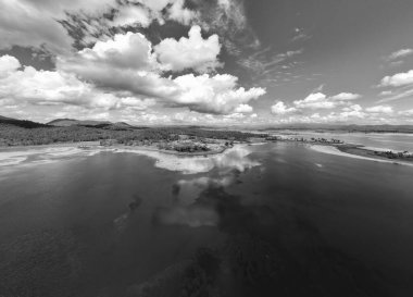 Sakin bir günde, su barajı boyunca uzanan inanılmaz bulutların monoton bir görüntüsü. Başımızın üstündeki tüylü yumuşaklık suda yansıyor..