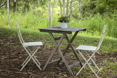 Eski bir ahşap masa ve bir kahve dükkanının bahçesinde teneke sandalyeler..