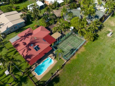 Blacks Beach, Mackay, Queensland, Avustralya - Nisan 2022: İHA havuzu yüzme havuzu ve tenis kortu olan bir sahil beldesindeki binaların çatılarına bakıyor.