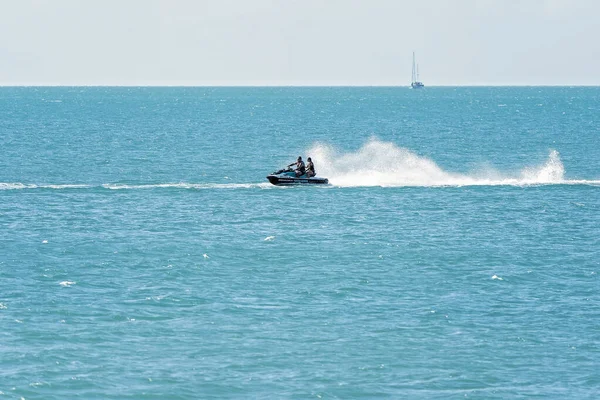 Airlie Beach, WhitSunday, Queensland, Avustralya - Nisan 2022: Mükemmel bir yaz gününde arka planda bir yelkenli yatıyla okyanusu aşan iki kişi